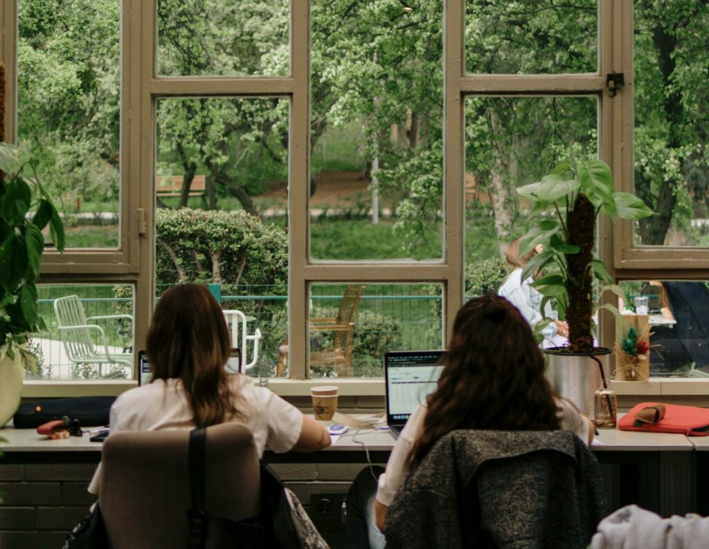 Office interior with large windows overlooking a lush green garden, providing a calm work environment.