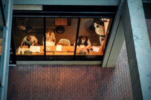 Aerial view of people working inside a modern coffee shop with large windows offering a top view.
